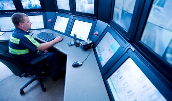 A male security officer watching surveillance cameras